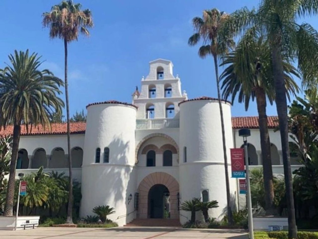 San Diego State University mit ikonischer weißer Fassade und Palmen bei strahlendem Sonnenschein.