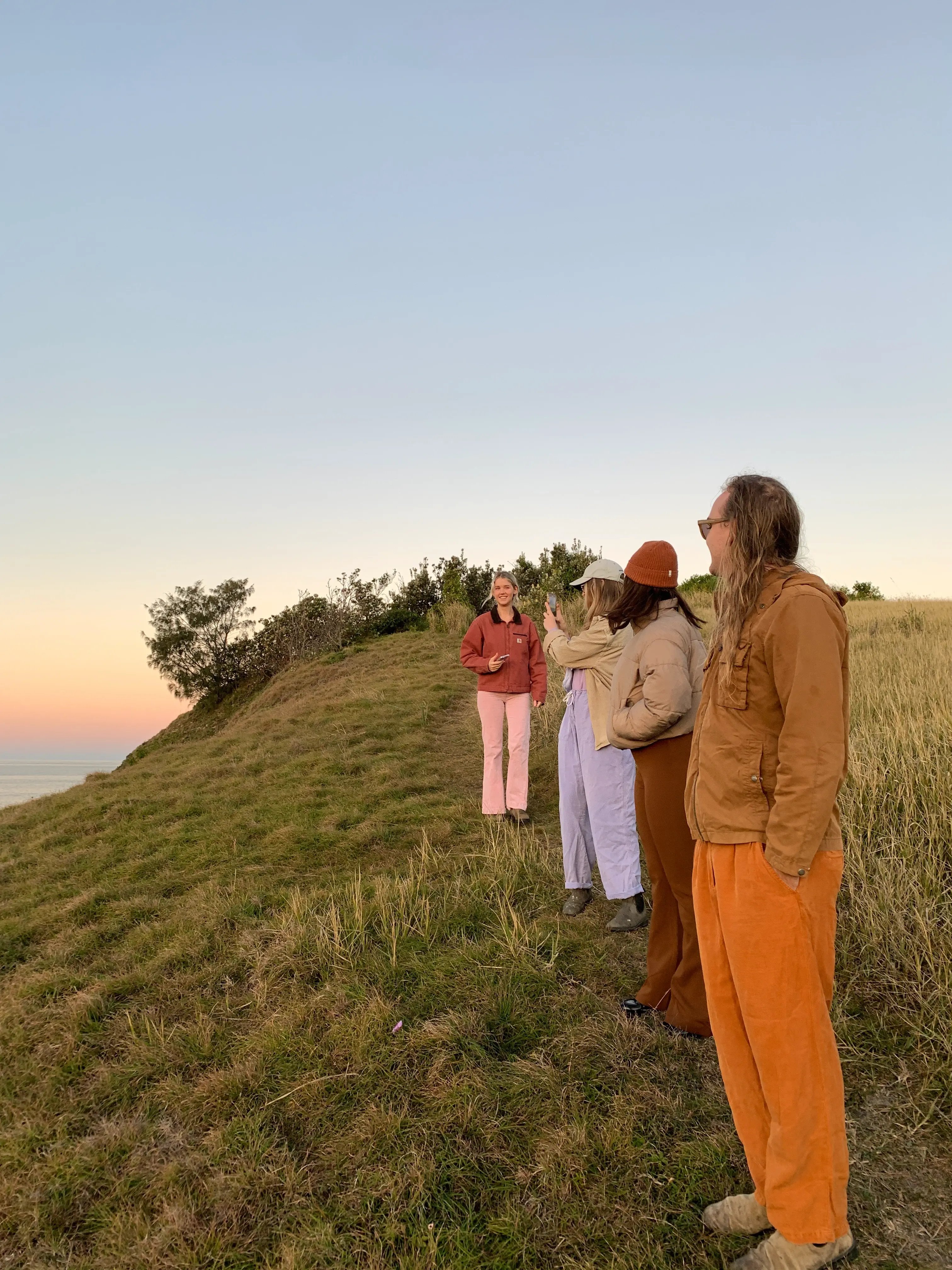 Gruppe junger Menschen auf einem Hügel bei Sonnenuntergang - Symbol für Aufbruch und neue Erfahrungen.