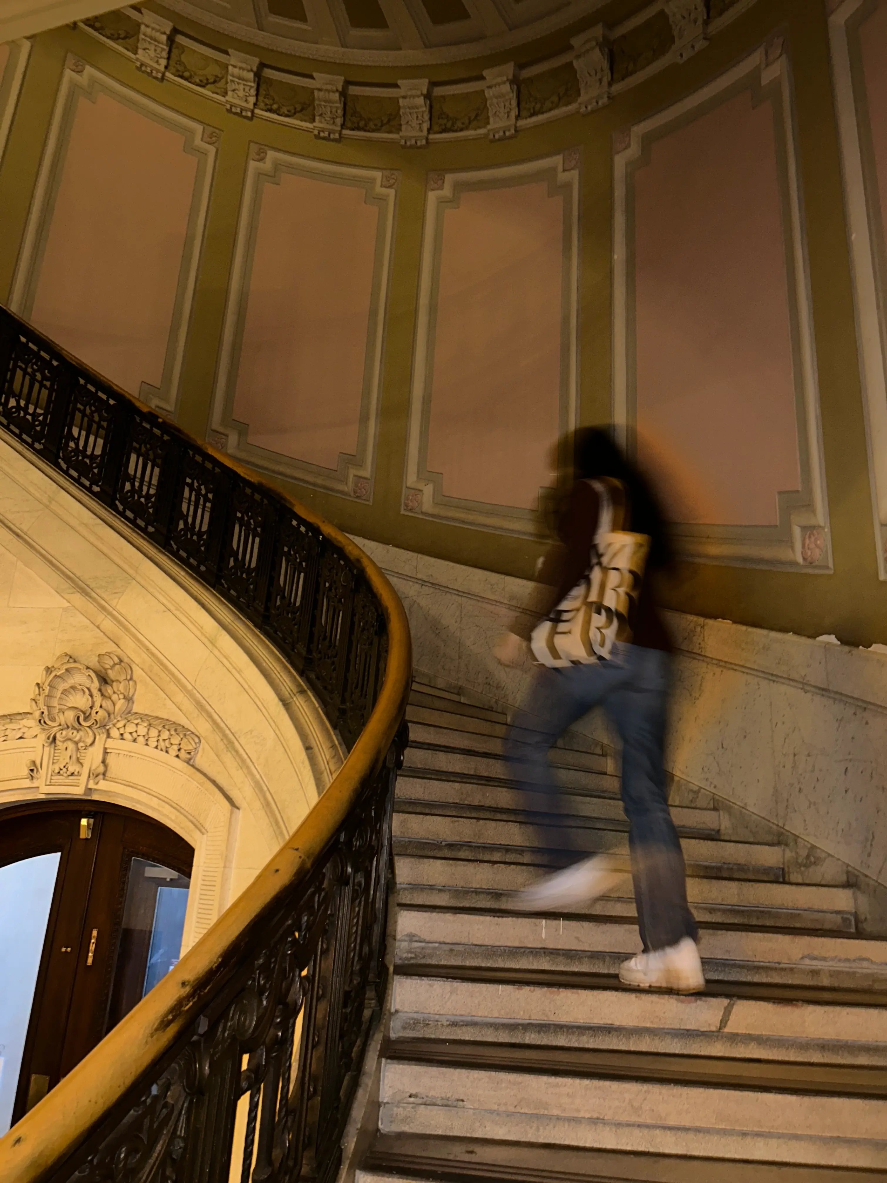 Studentin auf einer Treppe in einem historischen Gebäude.